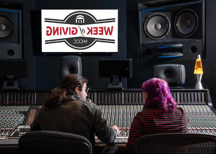 Two students sitting in front of a sound mixing board